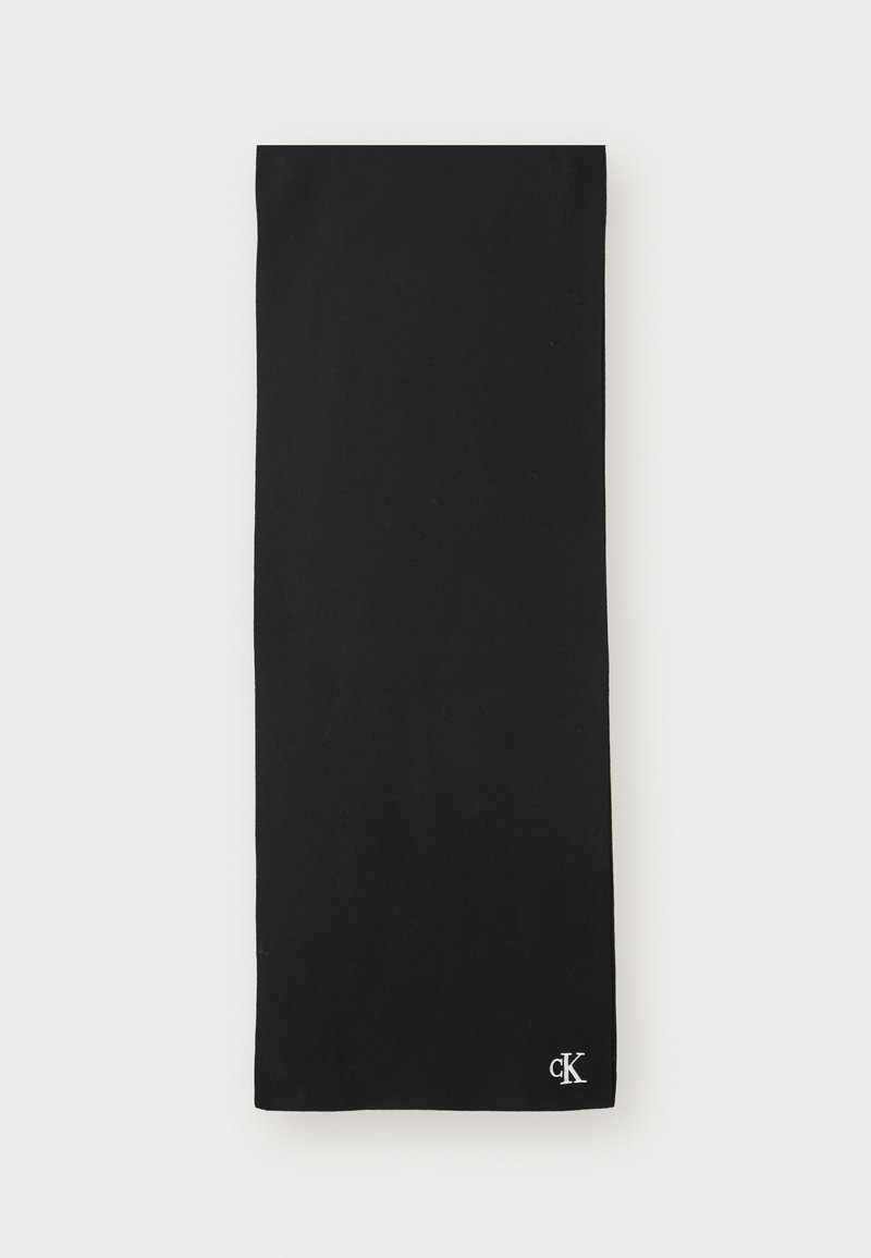 Svart, rektangulær skjerf laget av myk stoff. Har en liten hvit "ck"-logo i det nedre hjørnet. Glatt tekstur uten synlige mønstre.
