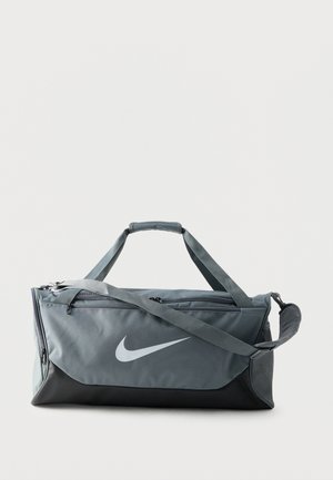 Šedo-čierna športová taška Nike s veľkým bielym logom Nike, dvojitými rukoväťami a nastaviteľným ramenným popruhom.