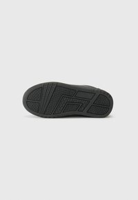 Semelle de chaussure en caoutchouc noire présentant une surface texturée avec des motifs de semelle variés et des lignes de design pour une meilleure adhérence et un soutien accru.