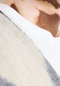 Textiltröja med vit halsringning, i en ullblandning i ljusgrått, mörkgrått och benvitt, med en mjuk textur och mönstervariation.