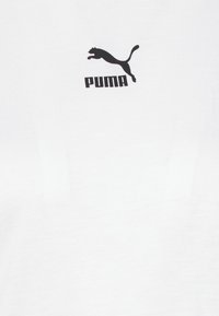 T-shirt bianco in cotone con logo Puma nero centrato sul petto, caratterizzato da una texture di tessuto semplice e liscia.