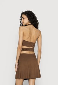 Conjunto castanho de duas peças com um top sem alças e um saia evasê. Feito de um tecido suave com uma cor sólida e detalhes mínimos.