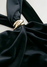 Sort fløjlstof snoet i midten, med en skinnende guld snoet metalaccent. Glat tekstur med en rig, dyb farve.