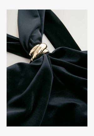 Juodas aksominis audinys, sukurtas į vidurį, su blizgia auksine metaline detale. Lygus paviršius su sodria, gilia spalva.