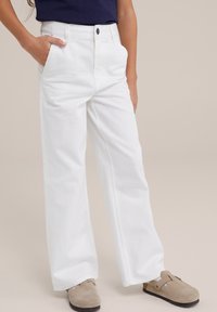 Witte denim broek met een rechte snit, voorzien van frontzakken, een knoopsluiting en contrasterende stiksels. Gepaard met grijze instap schoenen.