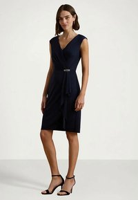 Mornarsko modra obleka do kolen z V-izrezom, kratkimi rokavi, drapirano sprednjo zasnovo in srebrnim poudarkom v pasu. Gladek material.