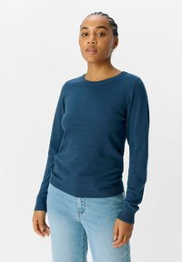 Pull en maille légère bleu marine, avec des manches longues, un col ras du cou, et des poignets et un ourlet côtelés.