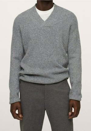 Szary sweter dzianinowy z dekoltem w serek, prążkowaną fakturą i długimi rękawami, zestawiony z szarymi spodniami o luźnym kroju i miękkim materiale.