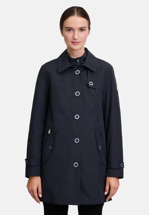 Navy waterproof coat with a collar, large buttons, two side pockets, and a zip pocket. Features a smooth fabric and tailored fit.