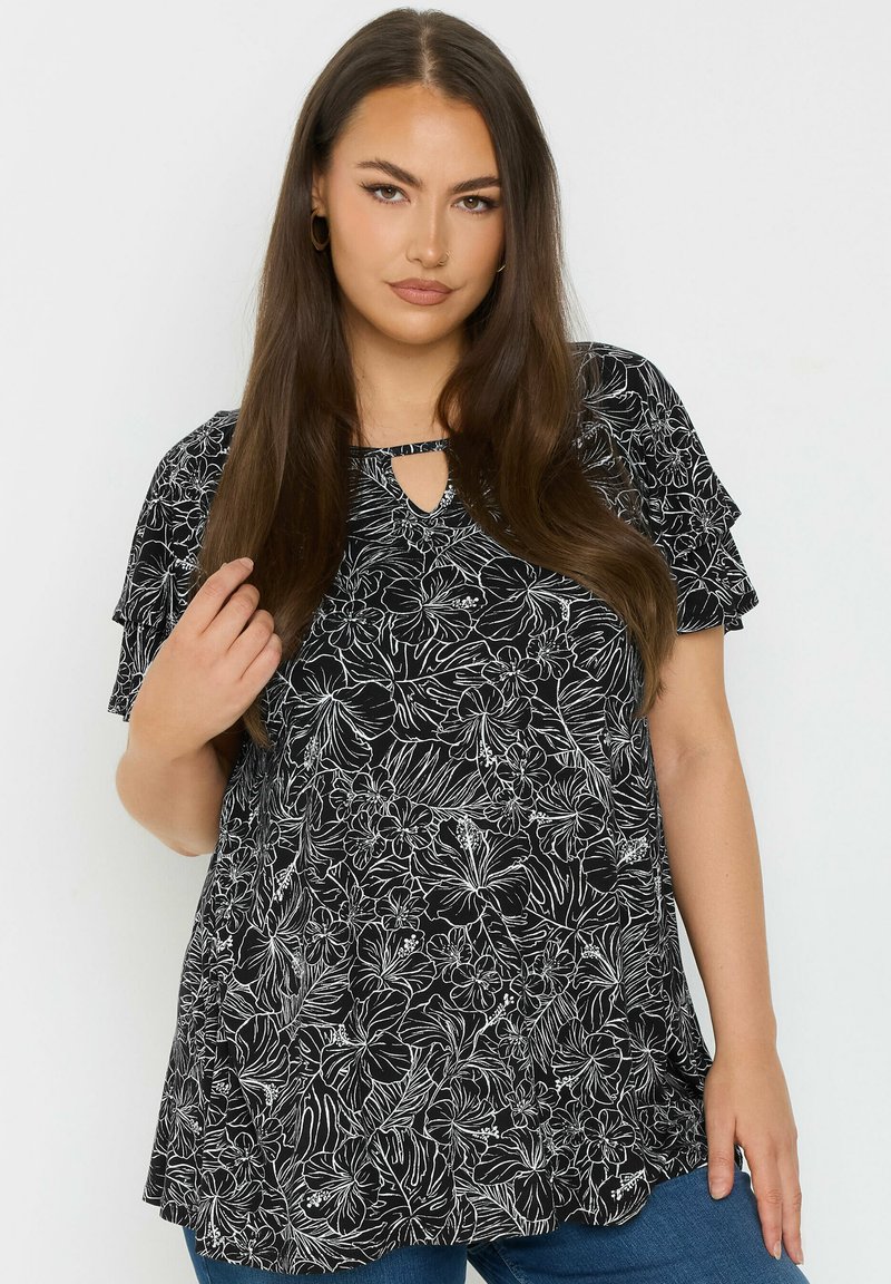 Blusa nera con motivi floreali bianchi, maniche corte a sbuffo, scollatura a chiave e vestibilità morbida, realizzata in tessuto leggero.
