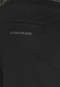 Černé legíny od Calvin Klein Jeans s hladkou texturou, elastickým pasem a jemným logem v šedé barvě.
