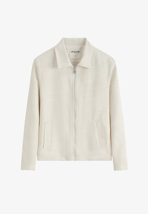 Veste crème avec une fermeture éclair devant, deux poches latérales, manches longues et col classique, en tissu texturé.