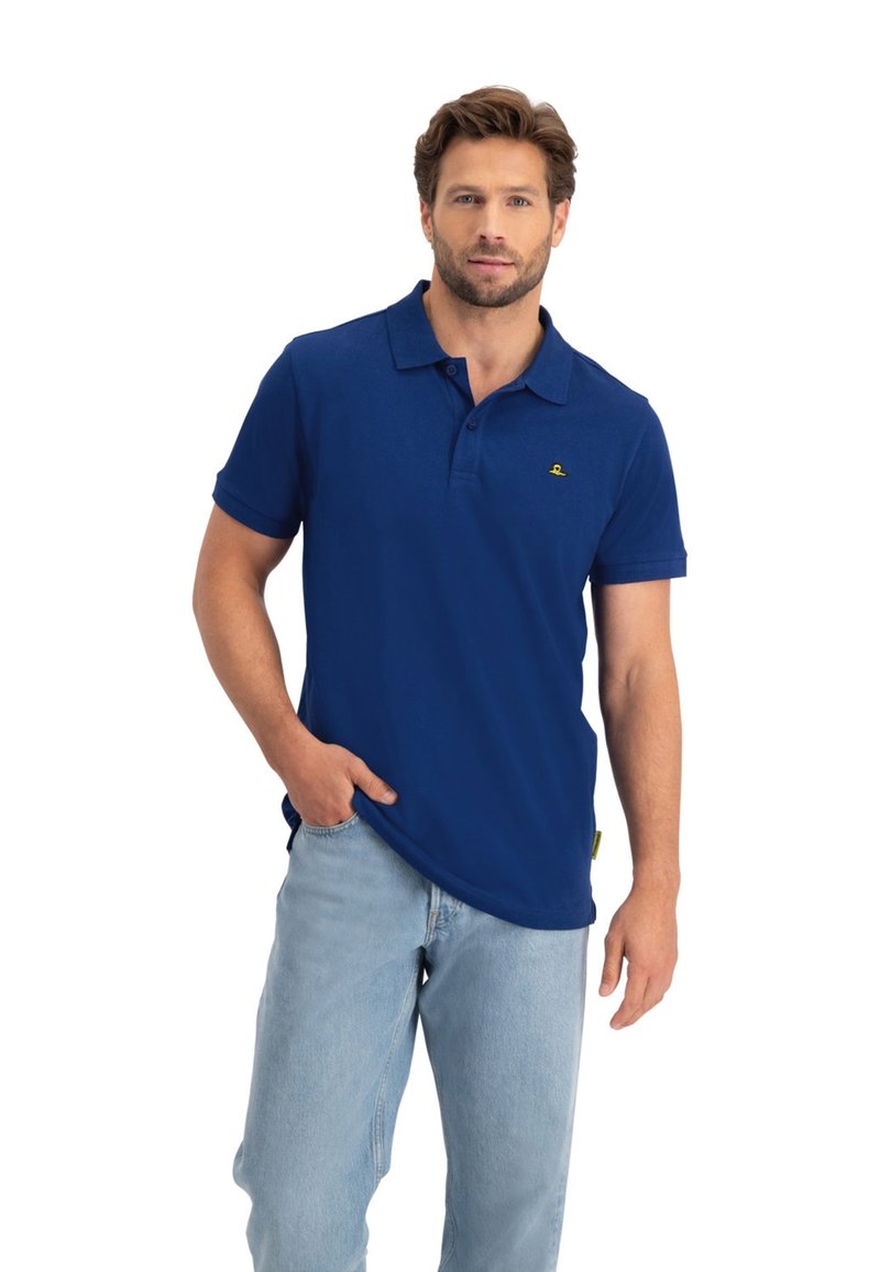 Marineblauwe polo gemaakt van katoen, met een kraag, korte mouwen en een klein geel logo op de borst. Gecombineerd met lichtblauwe jeans.