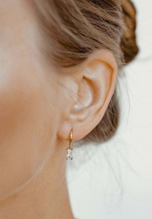 Gold hoop earring featuring a clear rectangular stone accent, hanging below the hoop, with a smooth, polished finish.