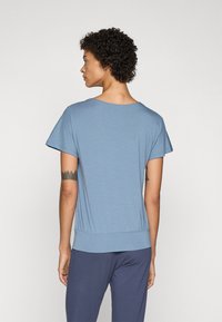 Light blue short-sleeve top with a relaxed fit, round neckline, and gathered hem. Soft fabric and smooth texture. Simple design.