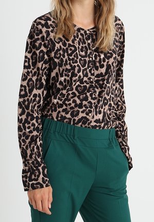 Blouse à imprimé léopard en tissu lisse, avec un devant à boutons et des manches longues, assortie à un pantalon taille haute vert.