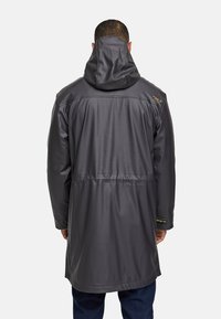 Abrigo impermeable gris oscuro con un alto cuello y capucha, que presenta una cintura ceñida y una textura suave. Notables acentos dorados en los hombros.