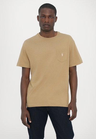 T-shirt en khaki à manches courtes en coton avec un col rond et une petite poche poitrine comportant un logo brodé en blanc.