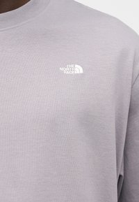 Ανοιχτό γκρι φούτερ με ραβδωτή υφή και μικρό λευκό λογότυπο "The North Face" στην α ριστερή περιοχή του στήθους. Κλασικός σχεδιασμός με στρογγυλή λαιμόκοψη.