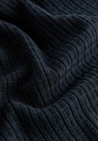 Marineblauer Stoff mit Textur und Gittermuster, zeigt weiche, gewebte Fasern und sanften Fall. Das Material wirkt gemütlich und leicht.