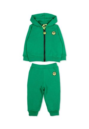 Ensemble sweat à capuche et pantalon taille bébé vert avec des patchs de visage souriant jaune sur la poitrine, la tirette de la fermeture éclair et la poche, posé à plat sur fond blanc.