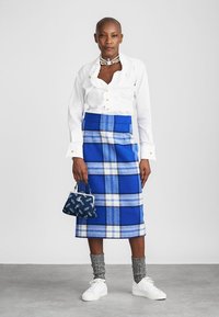 Sinine ruuduline villaseelik valgete ja hallide aktsentidega, kombineeritud valge volangilise särgi, hallide mustriliste sokkide ja valgete tennistega.