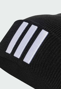 Černá pletená čepice se třemi svislými bílými pruhy. Texturovaný materiál s těsným střihem. Jednoduchý design bez dalších vzorů nebo detailů.