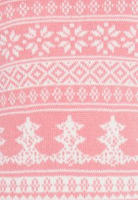 Suéter de punto con un fondo rosa y patrones geométricos blancos, que incluyen estrellas y árboles en un diseño repetido.