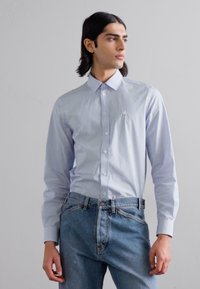 Lichtblauw gestreept overhemd met knopen, een kraag, lange mouwen en een klein geborduurd logo op de borst, gecombineerd met lichtdenim jeans.