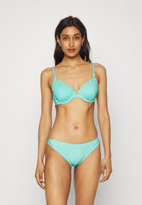 Tyrkysový bikini s vlnkovým dizajnom, hladkou látkou, podprsenkou s kosticami a nastaviteľnými ramienkami, a zodpovedajúcim dnom s vlnkovým dizajnom.