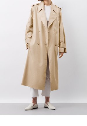 Beige vandtæt trench coat med dobbeltradet front, stor krave og sidelommer. Designet med brede ærmer og en afslappet pasform.