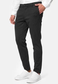 Dark gray tailored pants in a soft fabric, featuring a slim fit and smooth texture, paired with white sneakers for contrast.
