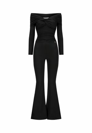 Combinaison noire épaules dénudées, manches longues, corsage froncé, taille ajustée et jambes de pantalon évasées.