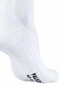 Chaussette de sport blanche avec un motif côtelé, un talon et un orteil renforcés, et des lettres noires sur la semelle. Offre un ajustement serré pour le confort.