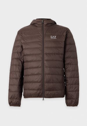 Un mannequin masculin porte une doudoune à capuche EA7 marron foncé, un pantalon de jogging crème avec logo et des baskets blanches sur un fond blanc uni.