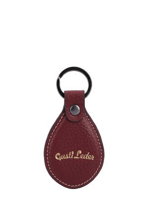 Llavero de cuero burdeos con forma de lágrima, costuras blancas, anilla metálica negra y texto dorado "Gusti Leder" en el frontal.