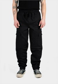 Pantaloni cargo negri cu talie cu șnur, dotati cu buzunare laterale și o croială lejeră. Construiți dintr-un material durabil, cu o suprafață texturată și cusături subtile.