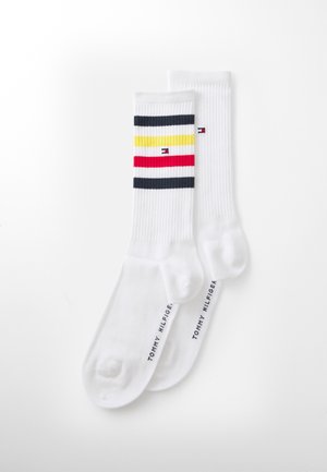Calcetines blancos de algodón con rayas horizontales en azul marino, rojo y amarillo. Incluyen el logo de la marca en la suela y tienen una textura acanalada.