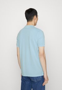 Jasnoniebieska koszulka polo wykonana z miękkiej bawełny, z klasycznym kołnierzykiem i krótkimi rękawami, z prostym dołem i bocznymi rozporkami.