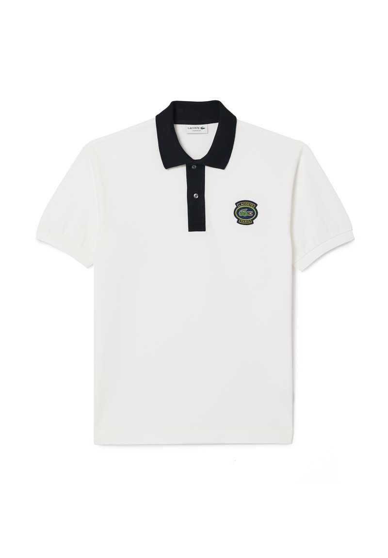 Chemise polo blanche avec un col noir et une patte de boutonnage à trois boutons, présentant un logo brodé vert et noir sur la poitrine gauche.