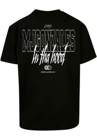 Black cotton T-shirt featuring bold white text. Front has "MJ Gonzales," while back displays "In tha hood." Simple, relaxed fit.