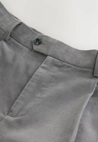 Pantalones de pana grises con corte recto, cierre de botón azul y sutiles rayas verticales. Textura suave con una cinturilla estructurada.