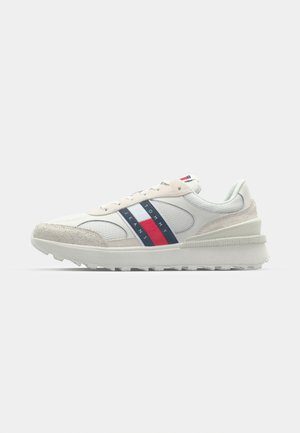 Herren Sportschuhe mit einem weißen Mesh-Obermaterial, grauen Wildlederakzenten, einer weißen Zwischensohle und rot-blauen Streifen auf den Seiten.