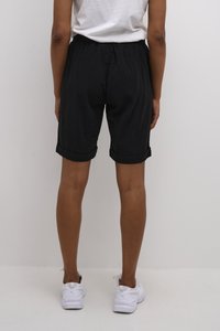 Shorts noirs à revers fabriqués en tissu léger, dotés d'une taille élastique et d'une coupe décontractée, associés à des baskets de sport blanches.