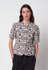 Korte mouwen blouse van crème stof met een geometrisch blauw patroon, voorzien van knoopsluiting en een losse pasvorm met plooidetail bij de taille.