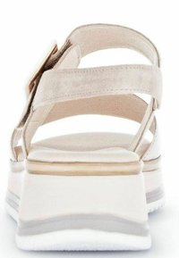 Beige suede sandal featuring wide straps, a cushioned sole, and a thick white and gray platform for added height and comfort.