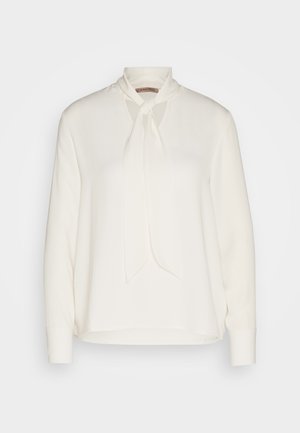 Blouse blanche à manches longues avec un design à col noué, présentant une texture lisse et une coupe décontractée. Simple et élégante, sans motifs supplémentaires.