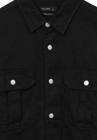 Camicia in denim nera con bottoni a pressione argentati, tasche sul petto doppie e design dal taglio regolare. Texture morbida e dettaglio del colletto a punta.