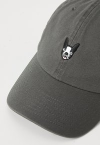 Casquette de baseball grise avec un visage de chien noir et blanc brodé à l'avant. Fabriquée en tissu lisse avec une visière courbée.