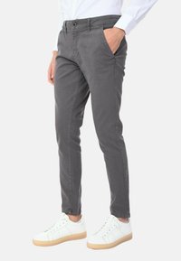 Chinos grigi slim-fit realizzati in morbido misto cotone, dotati di tasche laterali e chiusura a bottone. Abbinati a sneakers bianche.